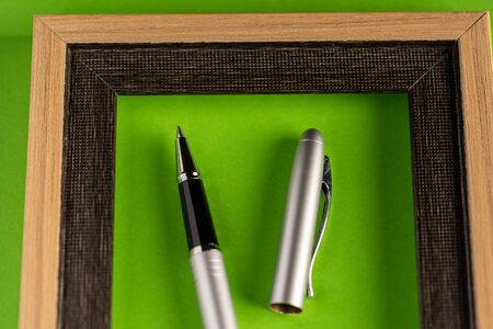 Classy silver pen and empty frame against green backgroundの写真素材