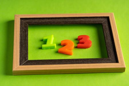 123 and empty photo frame against green background.の写真素材