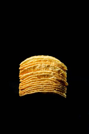 Delicious and crisp potato chips, isolated against black backgroundの写真素材