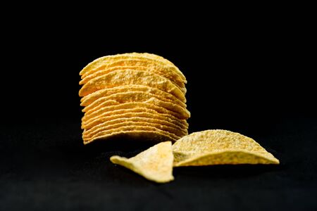 Delicious and crisp potato chips, isolated against black backgroundの写真素材