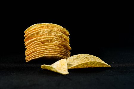 Delicious and crisp potato chips, isolated against black backgroundの写真素材