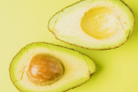 An avocado cut into half with green background