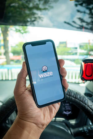 A man holding the iPhone X with Waze navigation app inside the car. Waze has gain popularity for its...