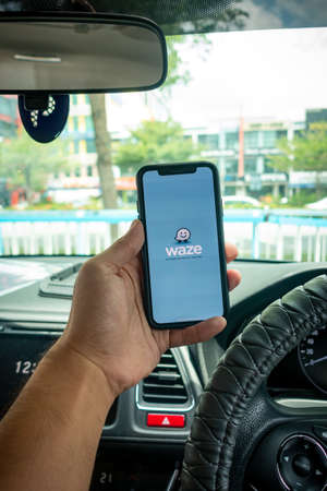 A man holding the iPhone X with Waze navigation app inside the car. Waze has gain popularity for its good navigation.のeditorial素材