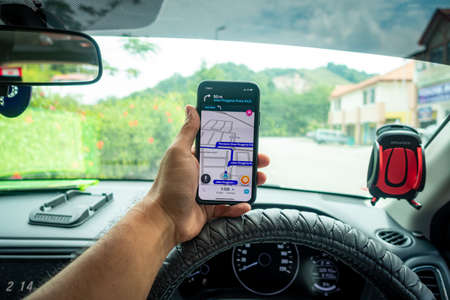 A man holding the iPhone X with Waze navigation app inside the car. Waze has gain popularity for its good navigation.のeditorial素材