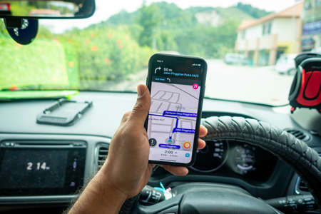 A man holding the iPhone X with Waze navigation app inside the car. Waze has gain popularity for its good navigation.のeditorial素材