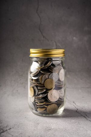 Savings concept: coins in jar with copy space for text