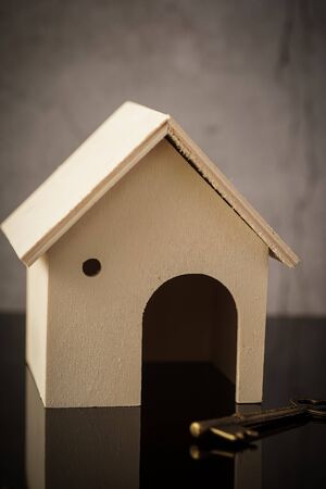 Home owning concept. Wooden house and key on a black backgroundの写真素材