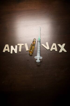 Anti-Vax wordings with empty syringe and vaccine ampoules on a wooden table, Vaccination concept, medicalの写真素材