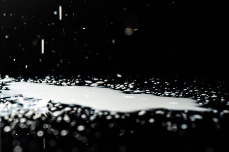 Milk spilled on black surface, closed up, selective focusの写真素材
