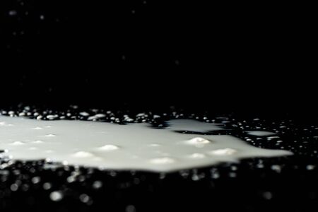 Milk spilled on black surface, closed up, selective focusの写真素材