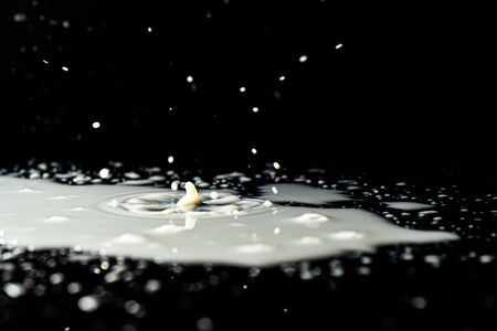 Milk spilled on black surface, closed up, selective focus
