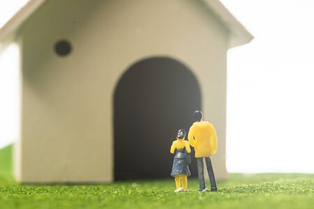 Miniature couple figures in front of a toy house, buying or owning a house conceptの写真素材