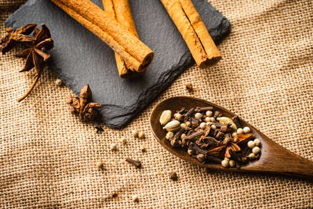 Various spices on a wooden spoon on top of a ragの写真素材