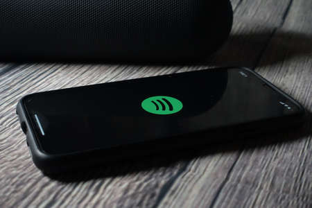 An iphone 11 screen showing spotify icon with beats pill speaker beside it