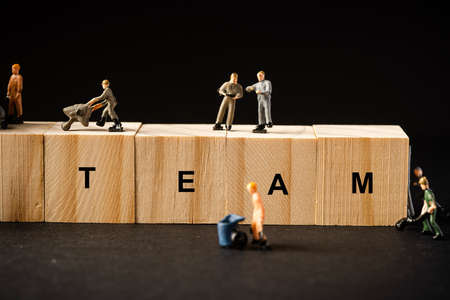 Teamwork concept. Miniature builders figure with wooden blocks with âTEAMâ wordingsの写真素材
