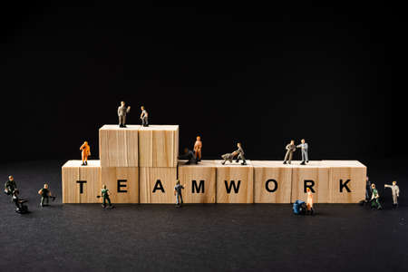 Teamwork concept. Miniature builders figure with wooden blocks with âTEAMWORKâ wordingsの写真素材