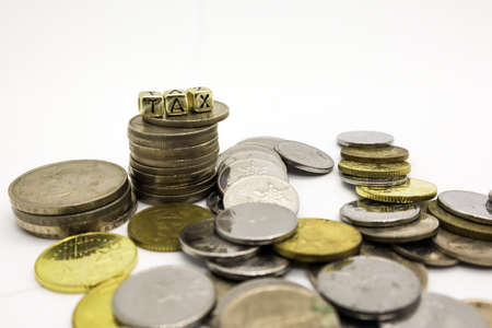âTAXâ wording on a stack of coins, isolatedの写真素材