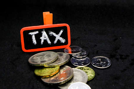 âTAXâ wording on a stack of coins, isolatedの写真素材
