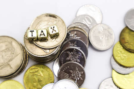 âTAXâ wording on a stack of coins, isolatedの写真素材