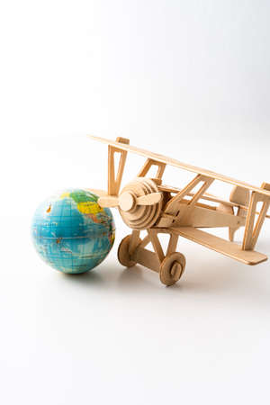 Miniature wooden aeroplane with a mini globe. Travel conceptの写真素材