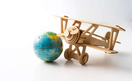 Miniature wooden aeroplane with a mini globe. Travel conceptの写真素材