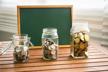 Saving concept: coins inside glass containers with chalkboard for copy spaceの写真素材