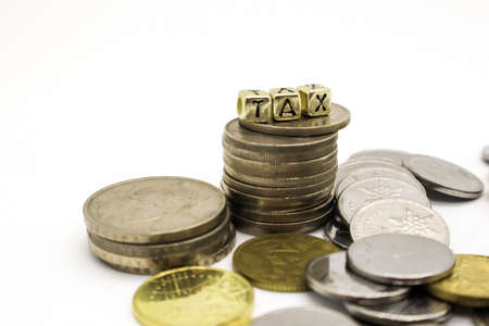 âTAXâ wording on a stack of coins, isolatedの写真素材