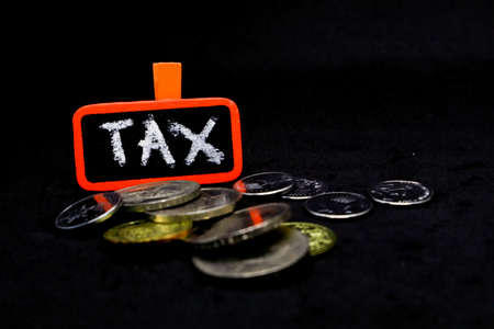 âTAXâ wording on a stack of coins, isolatedの写真素材
