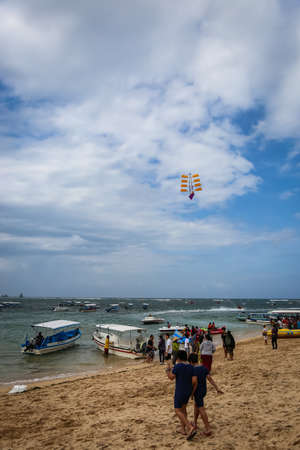 A wide angle shot at Pandawa Beach, Bali with parasols on sandy beach with strong waves at the ocean and a clody blue skyのeditorial素材