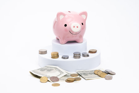 Piggy bank with scattered coins on white backgroundの写真素材