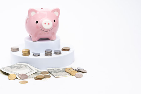 Piggy bank with scattered coins on white backgroundの写真素材