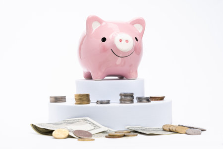 Piggy bank with scattered coins on white backgroundの写真素材
