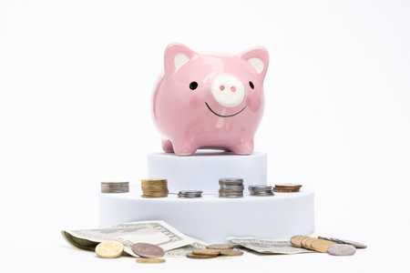 Piggy bank with scattered coins on white backgroundの写真素材