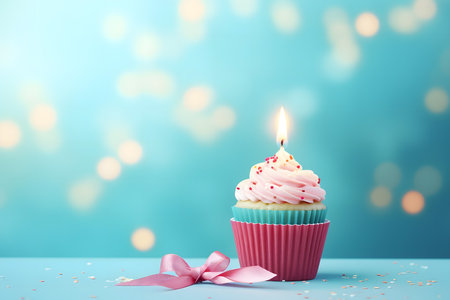 Birthday cupcake with pink buttercream frosting and pink ribbon on blue backgroundの素材