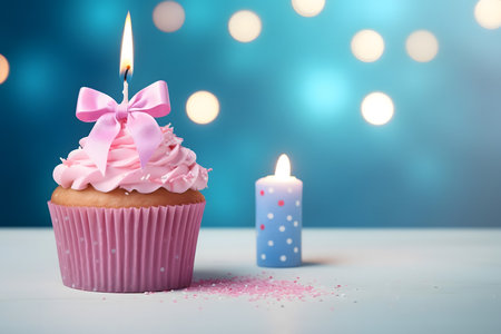 Birthday cupcake with pink buttercream frosting and candles on blue bokeh backgroundの素材