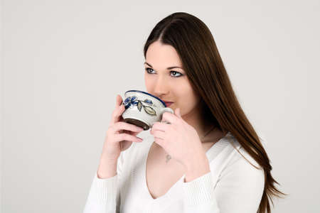 Young attractive white dressed girl drinking teaの写真素材