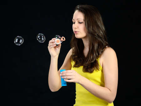 Pretty teenage girl blowing bubbles, black backgroundの写真素材
