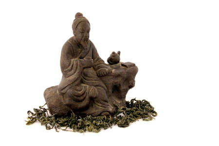 Japanese tea master statuette on white background and  with tea leaves aroundの写真素材