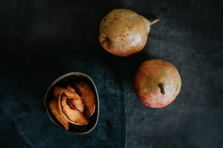Baked pears and two fresh pears from the garden on a dark backgroundの写真素材