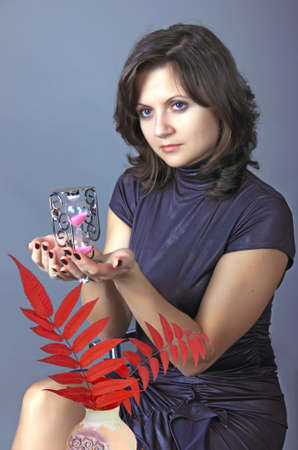 the young woman holds sand-glass in a hand 