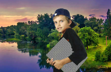 The boy with a folder against an evening landscape.の写真素材