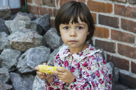 The little girl eat boiled corn.の写真素材