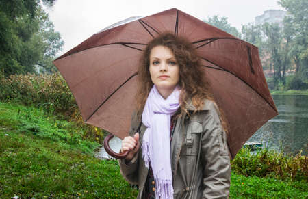 Girl with an umbrella walks on the bank of the river の写真素材