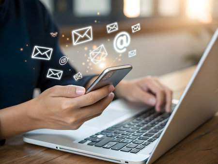 Woman hand using mobile phone and laptop computer with email icon on screenの素材