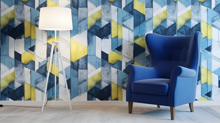 A stylish blue armchair with a high back is positioned against a wall adorned with a geometric pattern in shades of blue, yellow, and white. A tall, sleek floor lamp with a white shade stands to the left of the chair, casting a soft glow. The room has a minimalist and contemporary aesthetic, with a focus on clean lines and vibrant colors.の素材