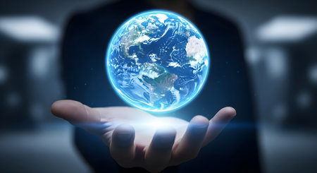 person holding a glowing blue earth in their hand with futuristic backgroundの素材