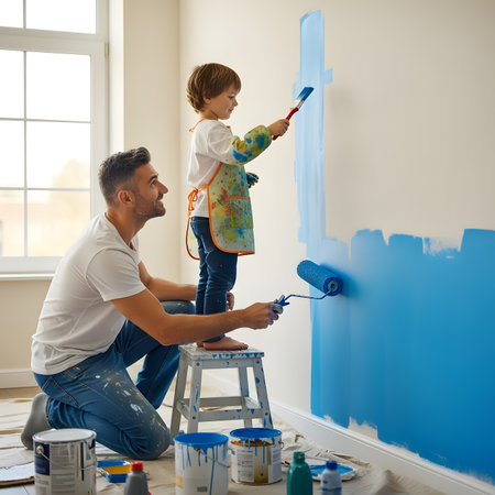 Father and son painting the wall in their new house. They are sitting on a ladder.の素材