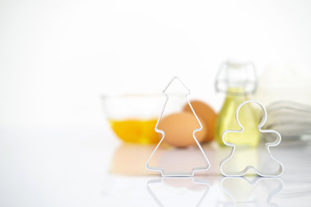 christmas Dessert ingredients and utensils on white reflect table background . Front view. Copy space. egg, flour, milk, oil, cookies cutter pine gingerbread man.Bannerの写真素材