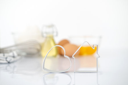 Dessert ingredients and utensils on white reflect table background . Front view. Copy space. egg, flour, milk, oil, Whisk, cookies cutter.の写真素材